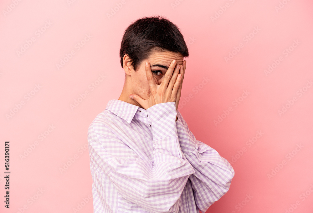 Young caucasian woman isolated on blue background blink through fingers frightened and nervous. Young caucasian woman isolated on blue background blink through fingers frightened and nervous.