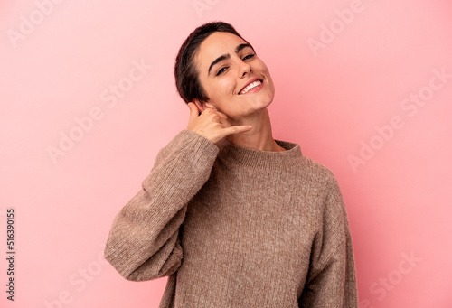 Young caucasian woman isolated on blue background showing a mobile phone call gesture with fingers.