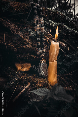 burning candle, a symbol of the moon, an amulet lying on the moss on a dark natural background. pagan wiccan, slavic traditions. Witchcraft, esoteric spiritual ritual for mabon.  photo