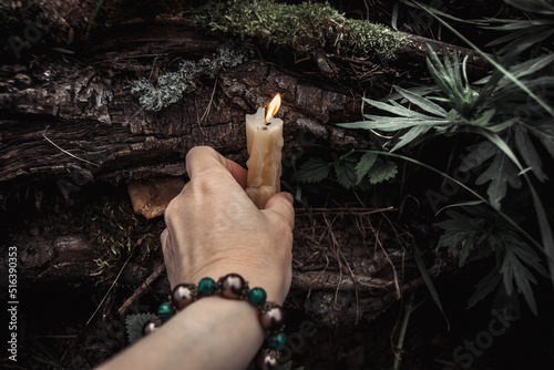 burning candles and a womans hand with a bracelet on a dark natural background. pagan wiccan, slavic traditions. Witchcraft, esoteric spiritual ritual for mabon, samhain. autumn equinox festival photo
