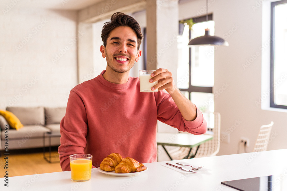 Young mixed race man eating croissant in a kitchen on the morning Young mixed race man eating croissant in a kitchen on the morning