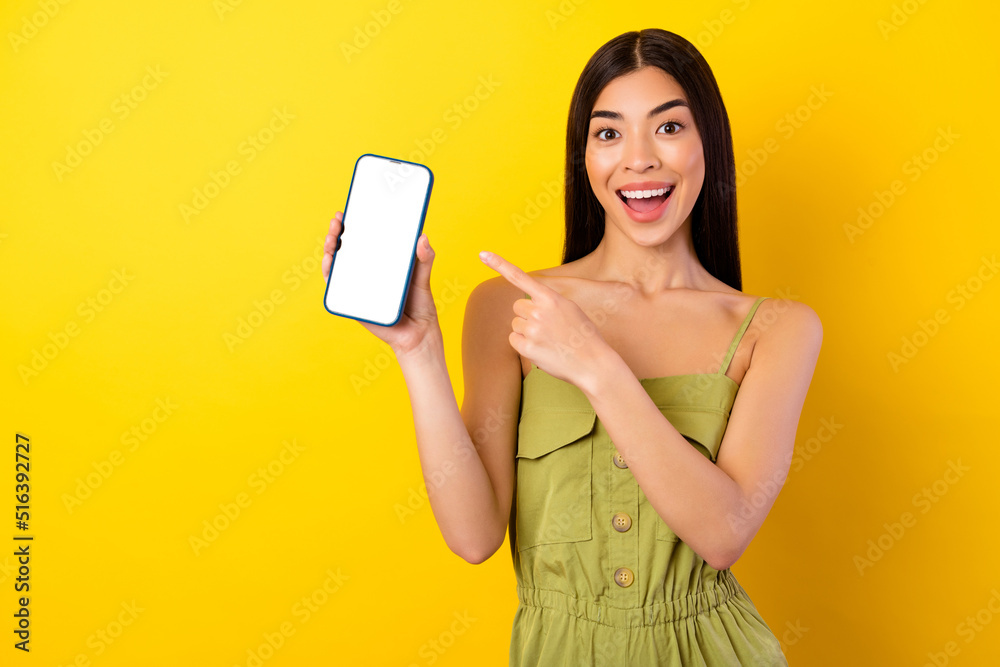 Naklejka premium Photo of charming astonished person direct finger empty space phone display isolated on yellow color background