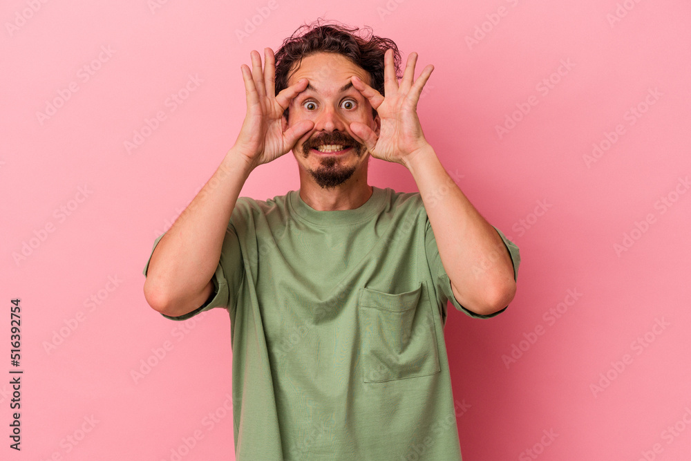 Young caucasian man isolated on pink background keeping eyes opened to find a success opportunity. Young caucasian man isolated on pink background keeping eyes opened to find a success opportunity.