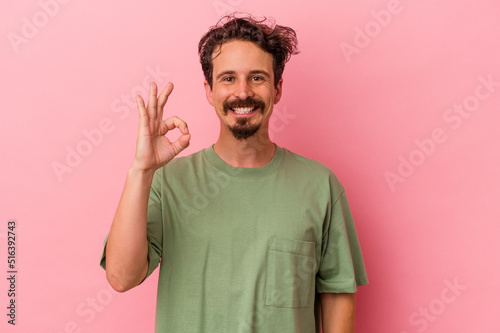 Young caucasian man isolated on pink background cheerful and confident showing ok gesture.