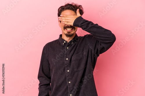 Young caucasian man isolated on pink background covers eyes with hands, smiles broadly waiting for a surprise. © Asier