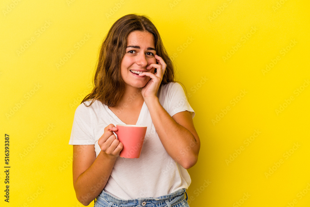 Young caucasian woman holding a mug isolated on yellow background biting fingernails, nervous and very anxious. Young caucasian woman holding a mug isolated on yellow background biting fingernails, nervous and very anxious.