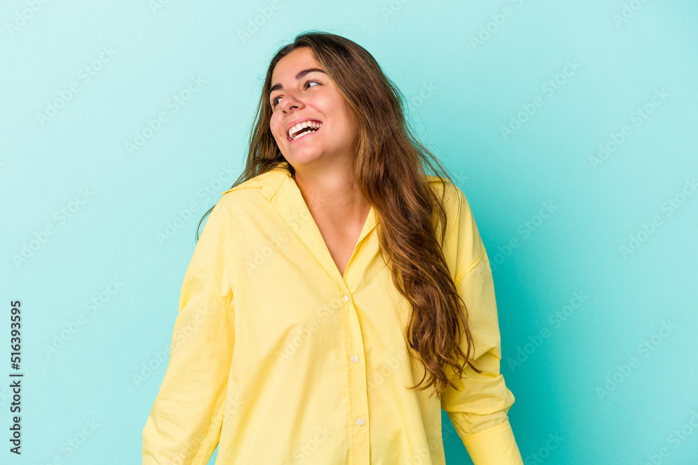Obraz premium Young caucasian woman isolated on blue background laughs and closes eyes, feels relaxed and happy.