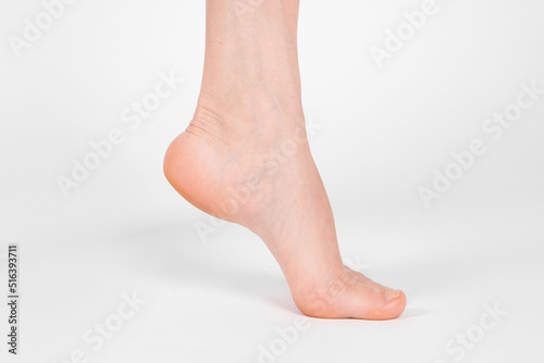 Barefoot and legs isolated on white background. Closeup shot of healthy beautiful female feet. Health and beauty concept. Side view of human foot ream with neutral manicure or pedicure. Sole of foot. © Maksim