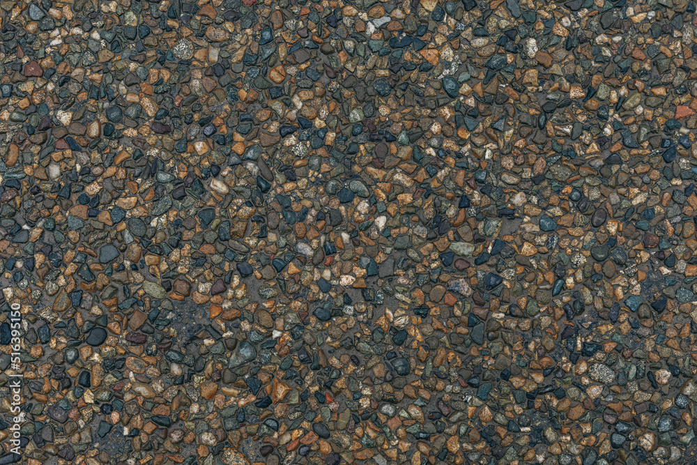 Texture of small multi-colored natural stone - river pebbles of gray and beige colors. sidewalk background. decorative coating for construction - wall and floor finishes in interiors