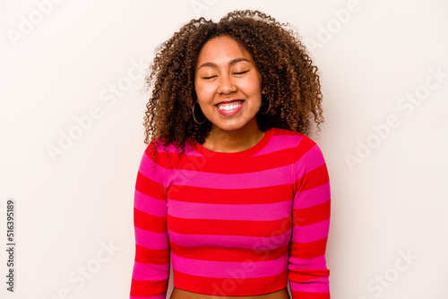 Young African American woman isolated on white background laughs and closes eyes, feels relaxed and happy.
