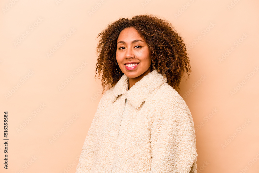 Young African American woman isolated on beige background confident keeping hands on hips.