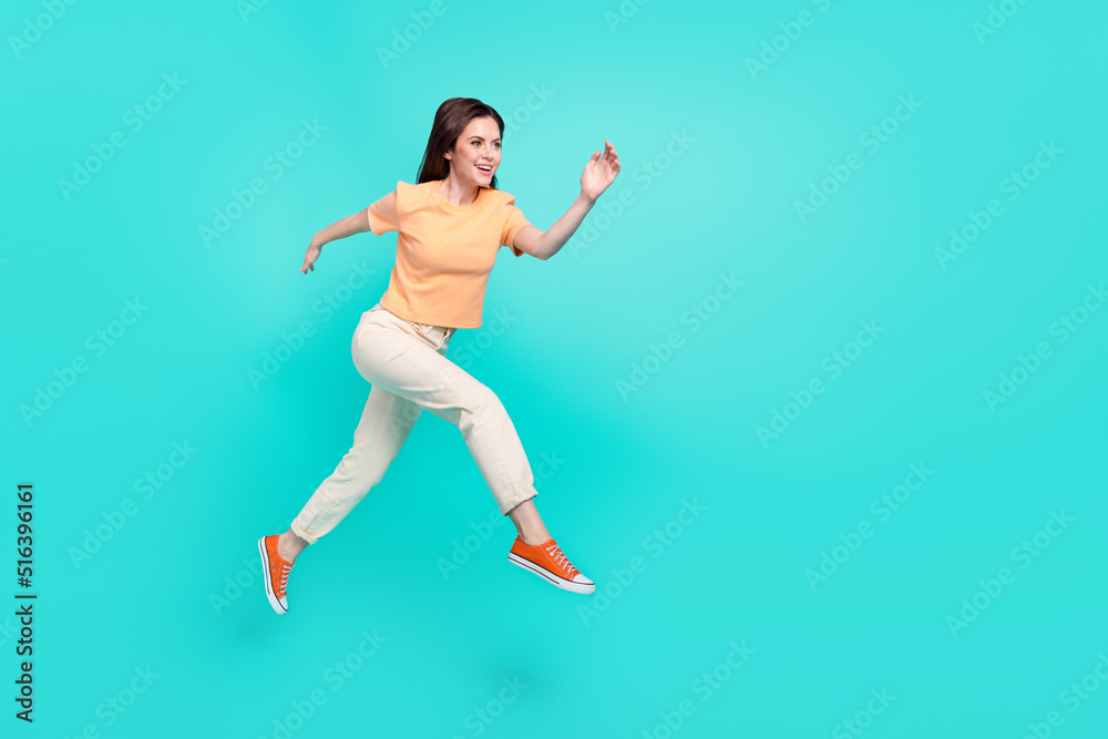 Full length photo of gorgeous satisfied girl run jump look empty space isolated on turquoise color background