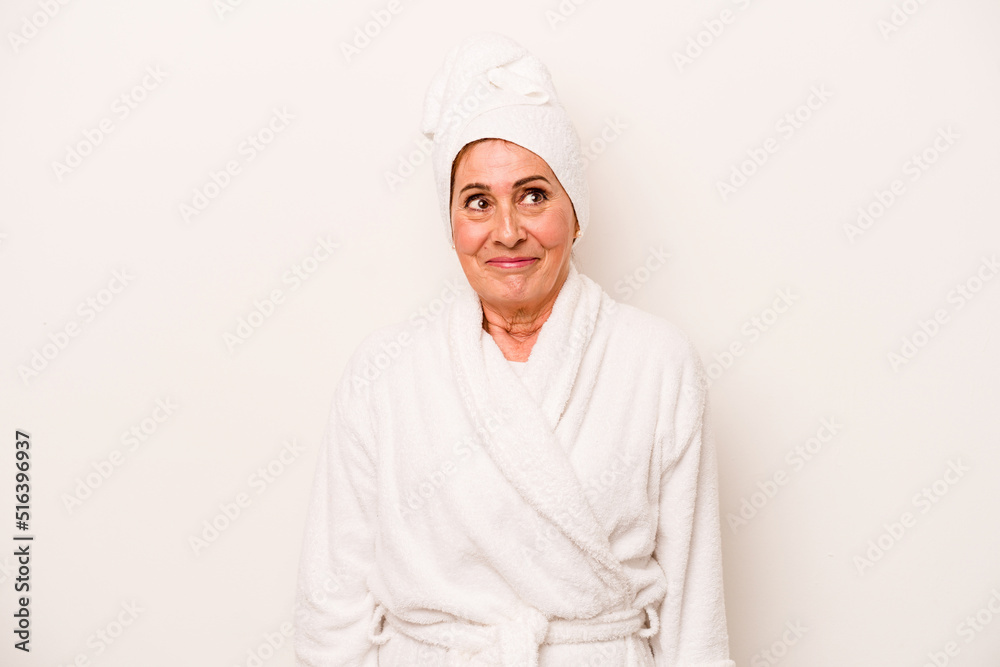 Middle age caucasian woman wearing a bathrobe isolated on white background dreaming of achieving goals and purposes