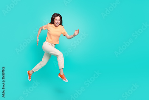 Full size profile portrait of glad nice lady running jump have good mood isolated on teal color background