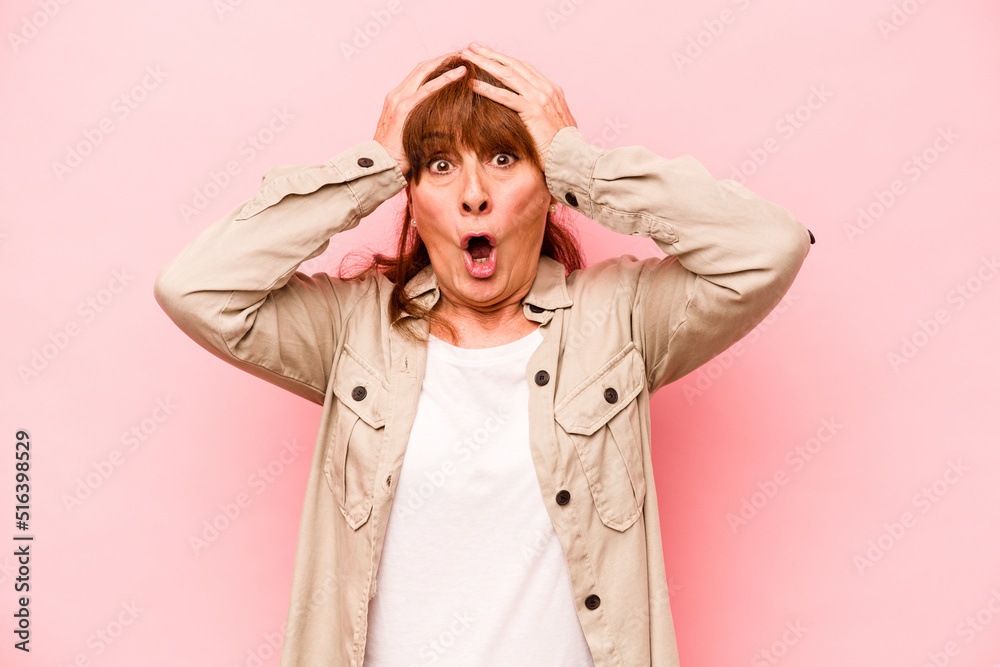 Middle age caucasian woman isolated on pink background surprised and shocked.