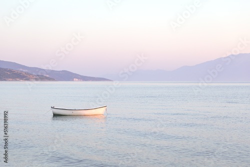 Tranquil pink sunrise or sunset over glowing sea ocean calm waters. Lonely boat. Sun low over horizon. water landscape. Copy space. Travel vacation destination scenics