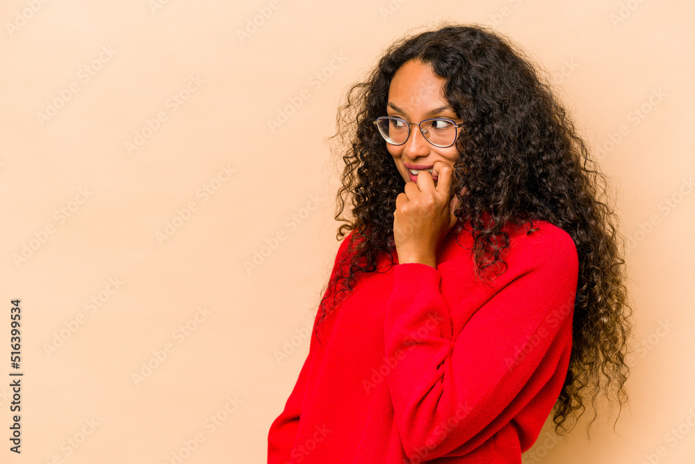 Young hispanic woman isolated on beige background relaxed thinking about something looking at a copy space.