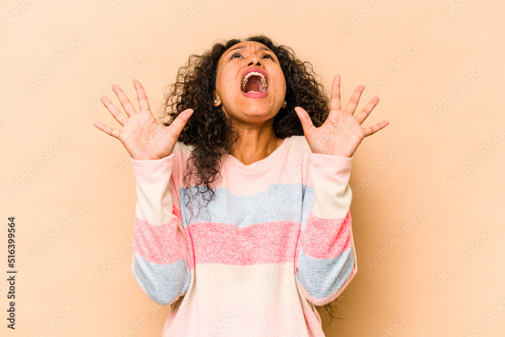 Young hispanic woman isolated on beige background screaming to the sky, looking up, frustrated. Young hispanic woman isolated on beige background screaming to the sky, looking up, frustrated.
