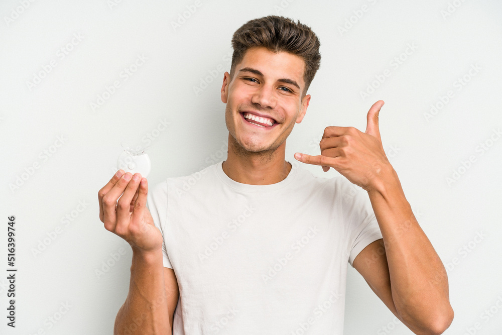 Young caucasian man hand sling isolated on white background showing a mobile phone call gesture with fingers. Young caucasian man hand sling isolated on white background showing a mobile phone call gesture with fingers.