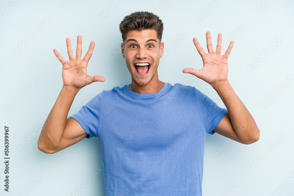 Young caucasian man isolated on blue background receiving a pleasant surprise, excited and raising hands. Young caucasian man isolated on blue background receiving a pleasant surprise, excited and raising hands.