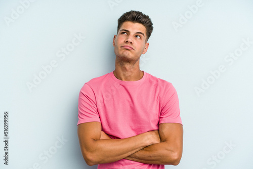 Young caucasian man isolated on blue background tired of a repetitive task.