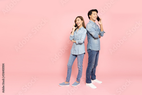 Portrait of young smiling Asian couple talking with mobile phone isolated on pink background, Asian Thai model