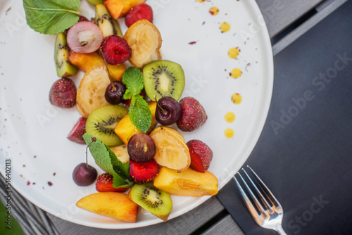 Fruit plate. Kiwi, bananas, cherries, strawberries and peaches on a plate