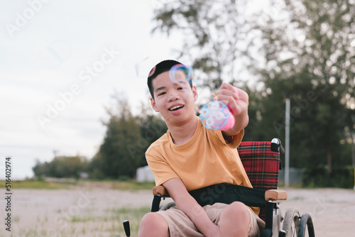 Fototapeta Naklejka Na Ścianę i Meble -  Young man with disability playing bubble shooter toy gun. It is a practice of using hand and finger muscles through play. One form of occupational therapy practice that develops good emotional skills.