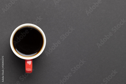 Image of red cup of hot black coffee on black background