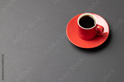 Image of red cup of hot black coffee on black background