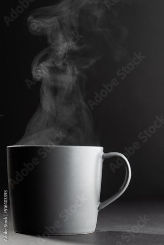 Image of grey cup of hot black coffee on black background