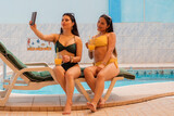 Autorretrato de turistas bonitos, elegantes, calientes, lindos y de moda, damas en trajes de baño con sonrisas radiantes disparando selfie juntas en la cámara frontal del teléfono inteligente, aislada