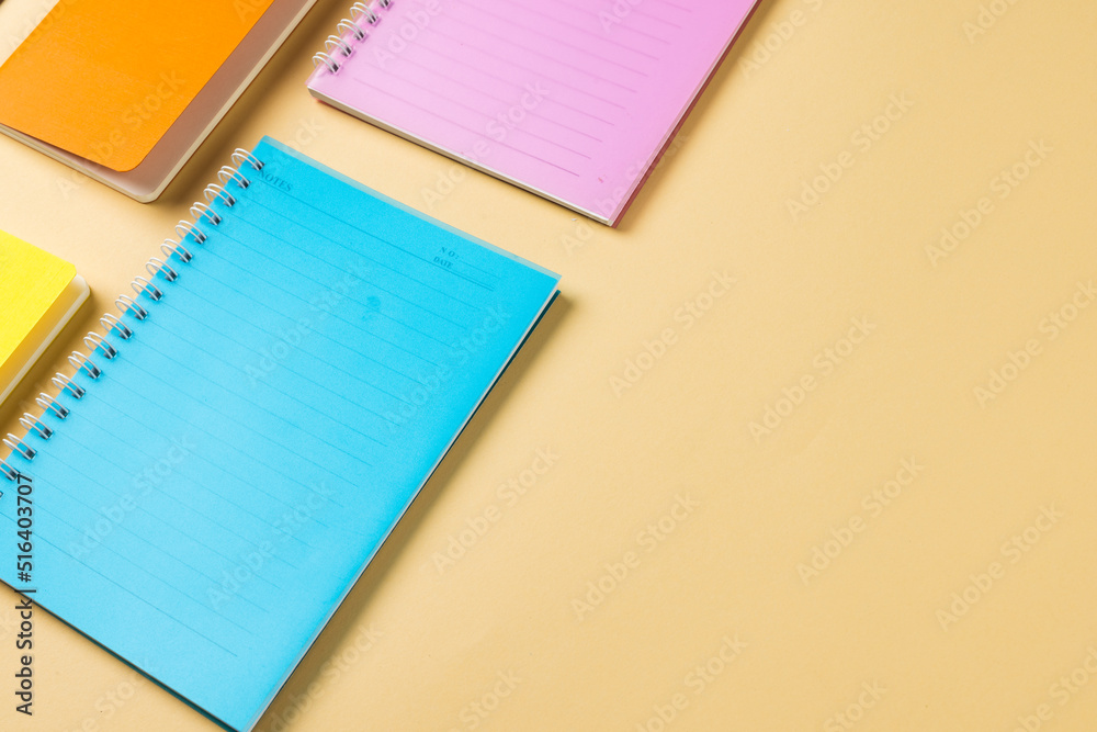 Composition of colorful notebooks lying on yellow surface with copy space Composition of colorful notebooks lying on yellow surface with copy space