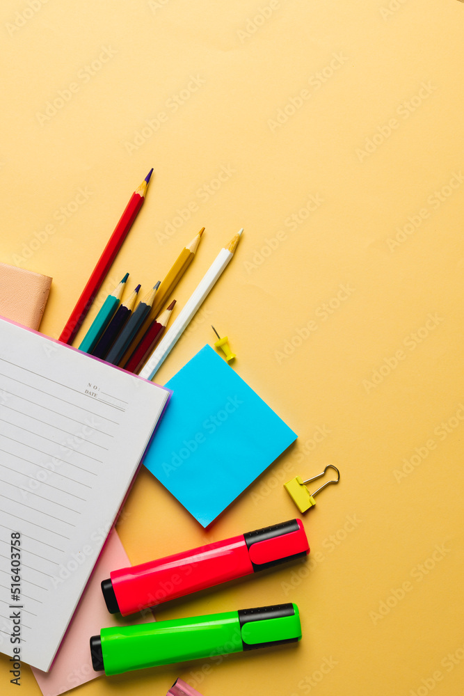 Vertical composition of notebook with copy space and school equipment on yellow surface Vertical composition of notebook with copy space and school equipment on yellow surface
