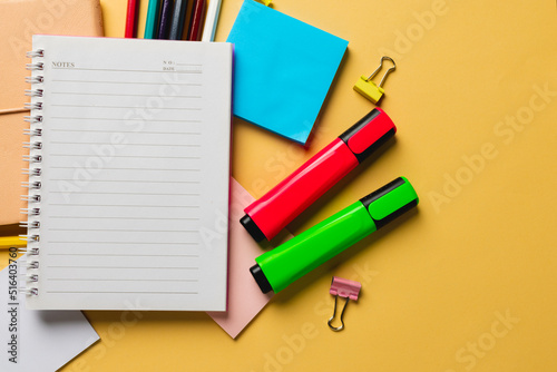 Composition of notebook with copy space and school equipment on yellow surface