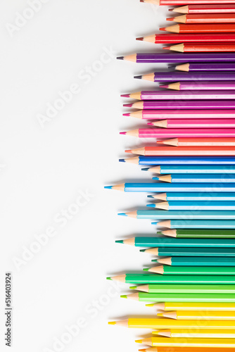 Vertical composition of colorful crayons on white surface with copy space