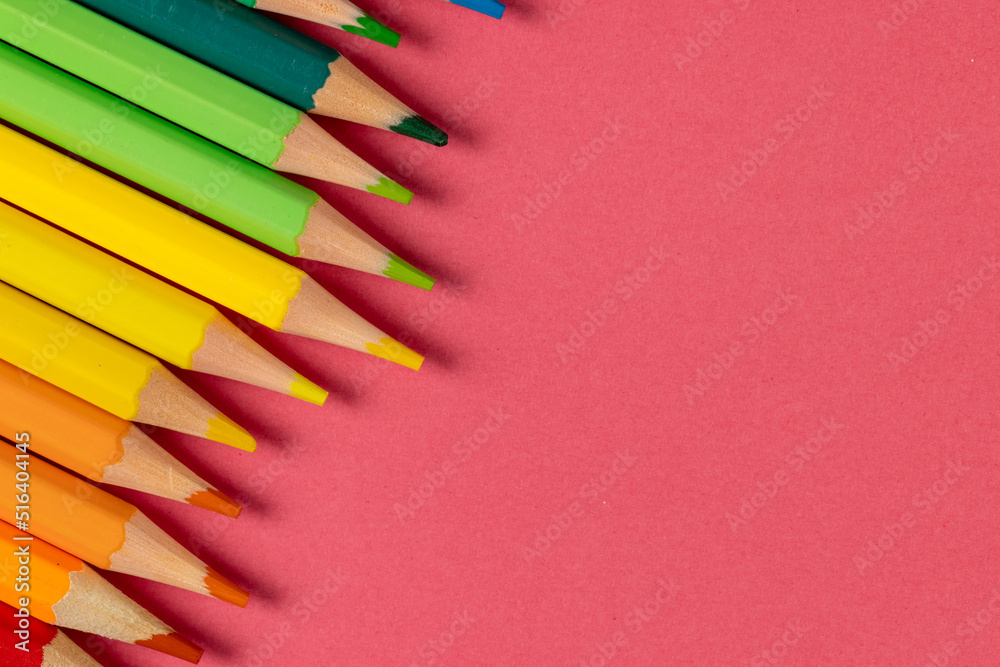 Composition of colorful crayons on pink surface with copy space
