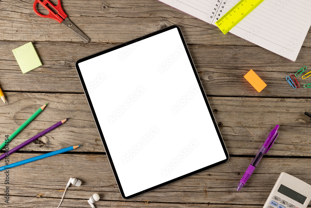 Composition of tablet with copy space and school items on wooden surface Composition of tablet with copy space and school items on wooden surface