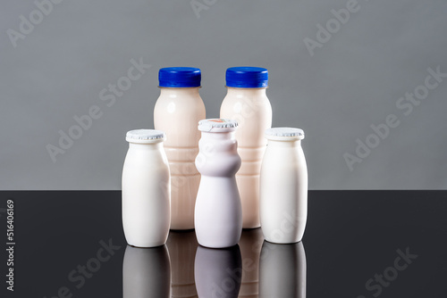 White flasks of yogurt in different sizes as a concept for probiotic products. Dairy products with probiotic content. Bifidobacteria improve immunity. Probiotics and vitamins to improve digestion