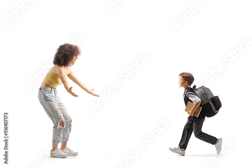 Full length profile shot of a schoolboy running towards a young woman