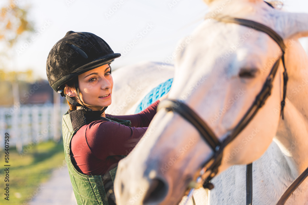 Obraz premium Portrait of a girl preparing her horse for riding.