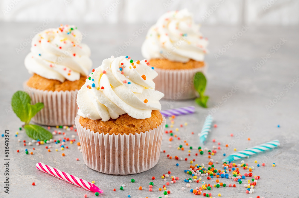 Delicious vanilla cupcakes with cream cheese and sugar candy on a gray background. Dessert for birthday. selective focus, copy space.