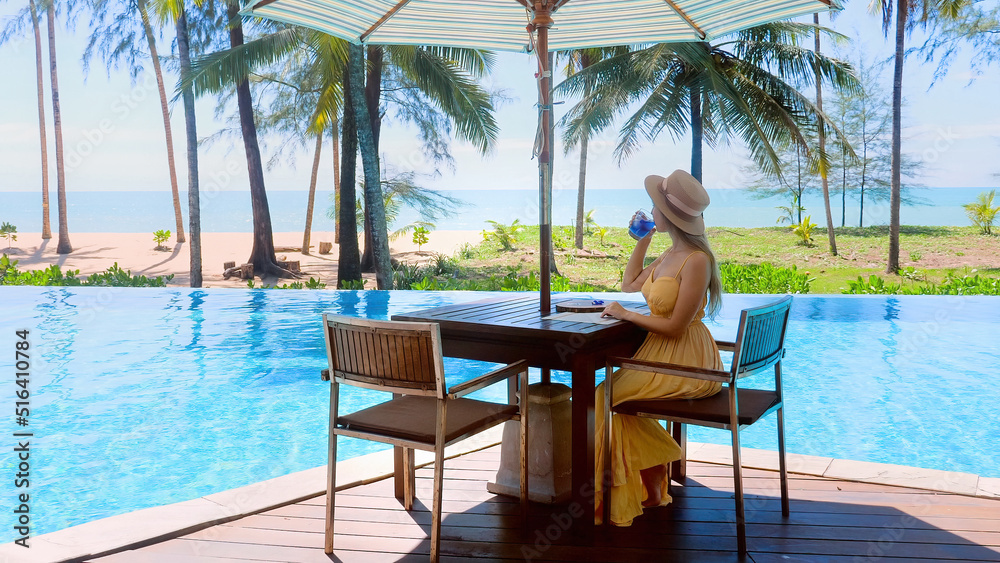 Young travel woman celebrating summer vacation. Female traveler relaxing in poolside cafe at luxury exotic hotel resort, enjoy beautiful sea view of mediterranean travel holiday.