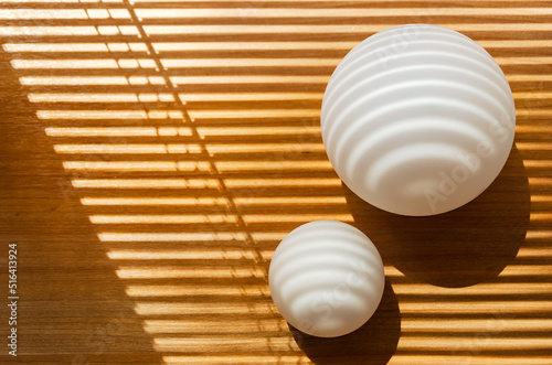 Straight and curved shadows on spherical surface of white ball and plane. abstract composition. white frosted glass balls with streaks of light and shadow from window with blinds. selective focus