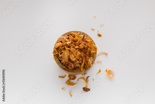 Fried shallot or bawang goreng in wooden bowl isolated on white background photo