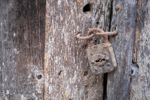 old rusty padlock with spider webs, on an old wooden door and in a pitiful state of a rustic house, rustic wood texture, selective focus, copy space