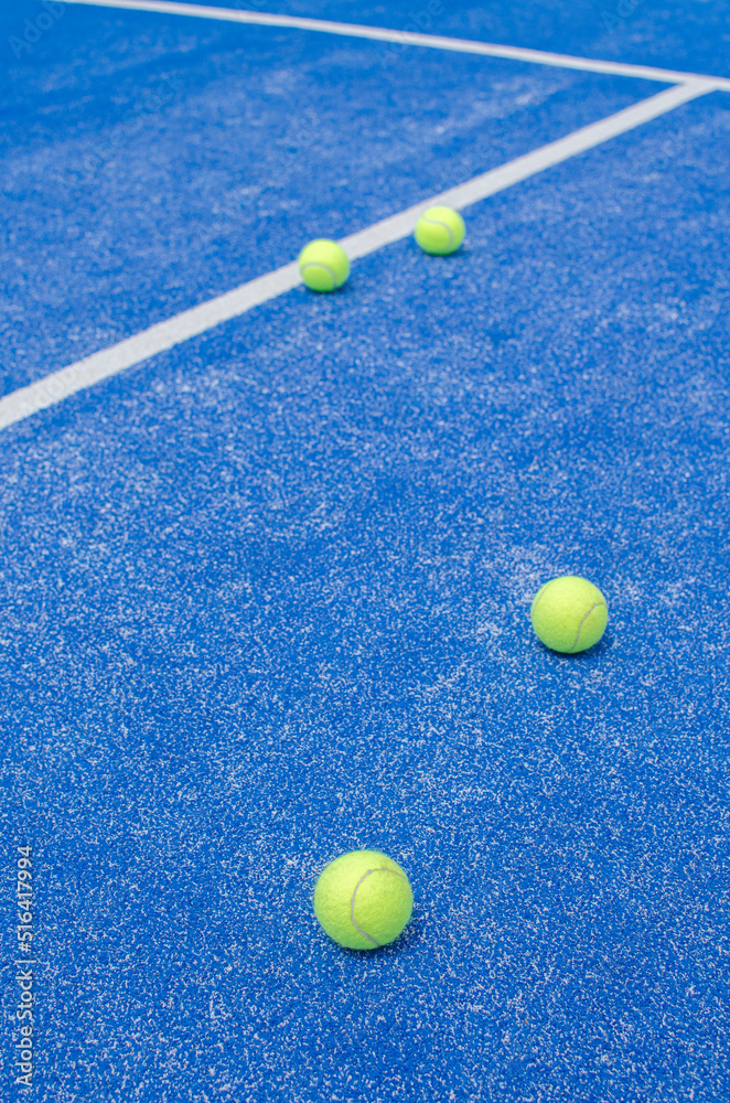 selective focus, several paddle tennis balls on a blue synthetic grass paddle tennis court