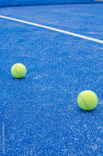 SELECTIVE FOCUS, TWO PADDLE TENNIS BALLS ON A BLUE PADDLE TENNIS COURT WITH SYNTHETIC GRASS © VicVaz