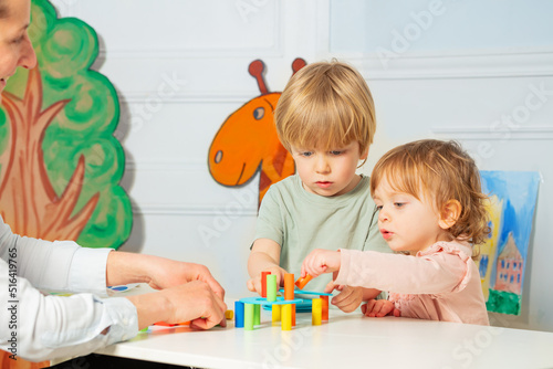 Woman and two little kindergarten kids build tower photo