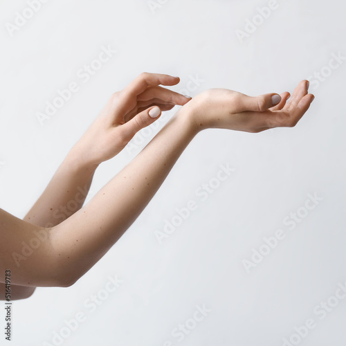  Woman gets beauty procedure for hands. Woman cares for the nails on hands. Beauty treatment of skin of hand. View of well-cared female hands on white background.    